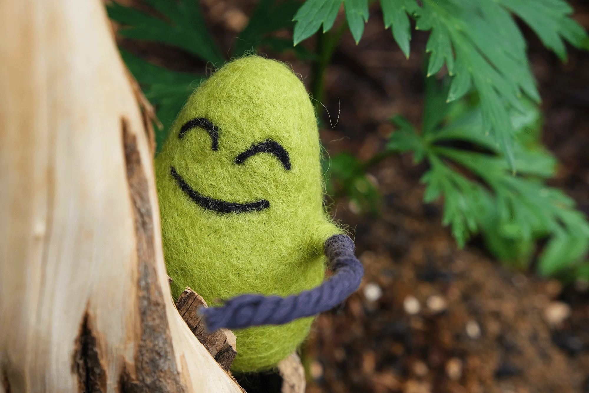 A felted Cloudia climbing a tree.